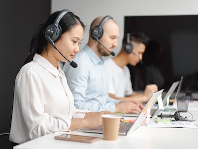 People with headsets on typing on laptops.